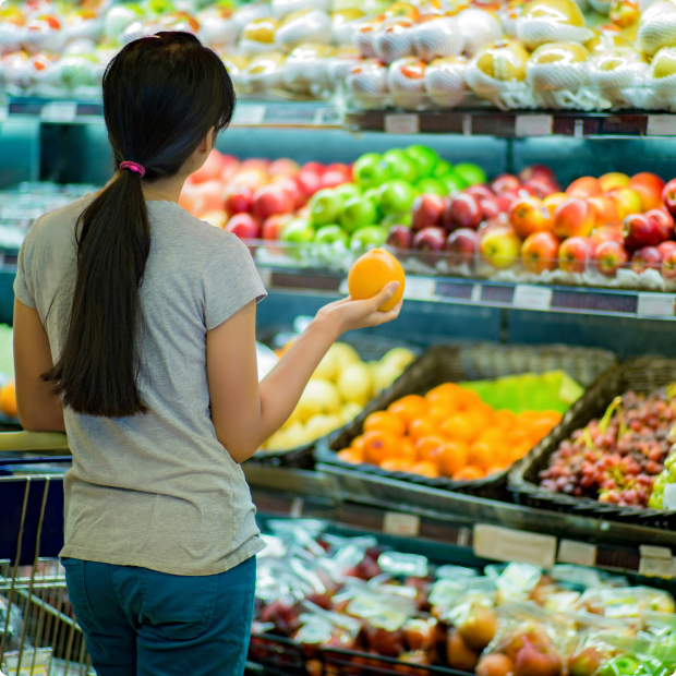 Consumer selecting fresh fruit in a supermarket, representing supply chain emissions in retail and food systems
